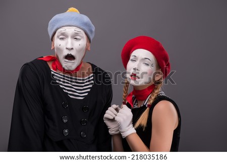 Waist-up portrait of sad mime couple crying with closed eyes, female mime touching her braid isolated on grey background with copy place