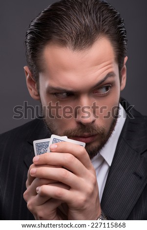 Handsome  confident man   holding cards  looking aside  having suspicion