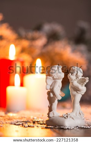 Christmas decoration   like angel porcelain statuettes   at red and white  lightning candles  and fir branches  with selective focus