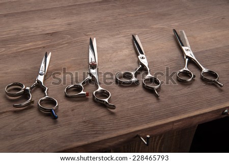 hairdressing equipment like different scissors  on brown  wooden table   in  professional  hairdressing salon