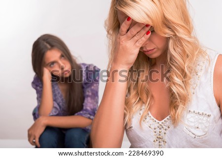 Young sad depressed  mother in the forefront  and daughter isolated on white background selective focus