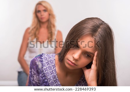 Young mother and sad depressed  daughter in the forefront  isolated on white background selective focus
