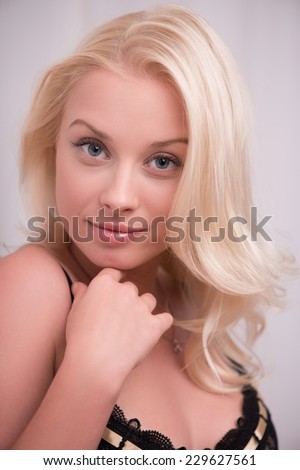 Portrait of sexy beautiful blond girl smiling with wavy hair in black underclothes  looking at camera   isolated on white background