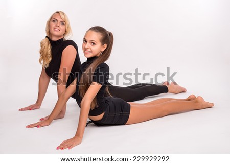 Young sport  mother and  daughter teenager stretching lying on stomach  push off  floor  smiling isolated on white background  with copy place