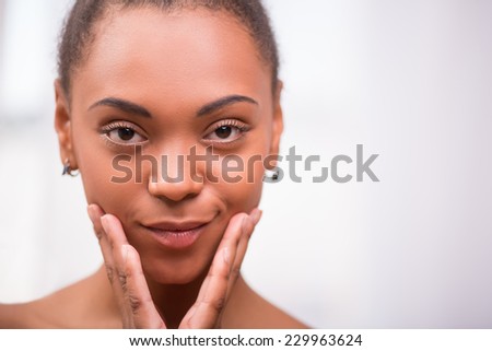 Portrait of beautiful  dark skinned girl being  puffed up touching her cheeks   looking at camera  isolated on white background  with copy place