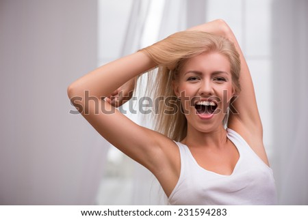 Portrait of beautiful happy blond girl with green  eyes  and straight  hair in white  T shirt  looking at camera smiling opening her mouth