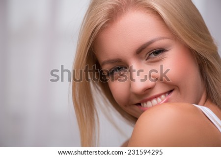 Portrait of beautiful  happy blond girl with green  eyes  and straight  hair in white  T shirt  looking at camera   smiling   with copy place  close up