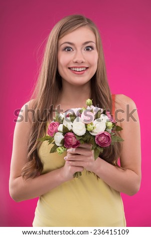 Portrait of happy beautiful brown haired girl holding  bunch of roses on rose background smiling looking at camera  waist up