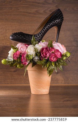 black classic  patent leather shoes  on bunch of roses on  brown parquet  wooden floor