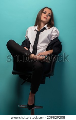 Full length portrait of young sexy woman wearing men suit oversize and tie holding jacket behind  her back, provocative look, interior shot