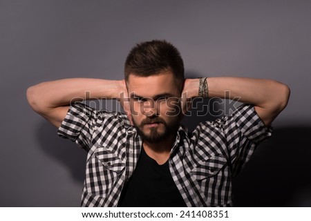 Too loud sound. Frustrated young man covering ears with hands and looking at camera while standing against white background