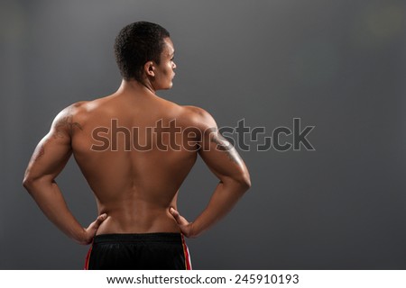 His body is perfect. Rear view of young shirtless African man with muscular body while standing against grey background