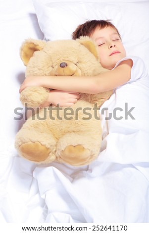 Sleeping angel. Portrait of an adorable little boy sleeping with a teddy bear in bed