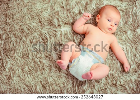 Curious little baby. Top view of cute baby wearing diapers lying on the fur blanket
