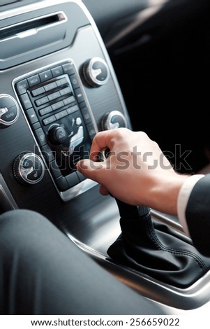 Driving a car. Top view closeup of a confident businessman in formalwear touching the gear shift while driving a car