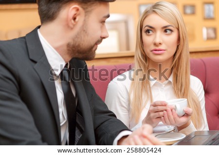 Business team at lunch. Handsome young man in suit and beautiful woman drinking coffee and looking at laptop while sitting at the restaurant