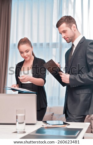 At the business meeting. Two cheerful business people in formal wear looking at the laptop together and pointing at something