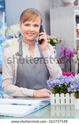 Thank you for your call. Young florist talks over the phone smiling at a camera