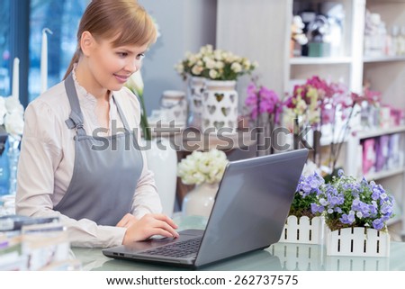 Flower business in action. Small business entrepreneur florist managing her business working by her laptop