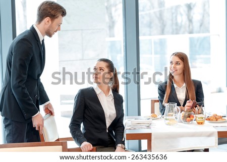 Such an anticipated meeting. Young businessman assists his female business partner to sit comfortably by lunch table