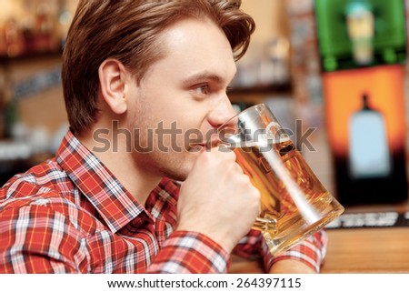 Tasting fresh brewed beer. Close up of a handsome young man tasting fresh beer from the mug