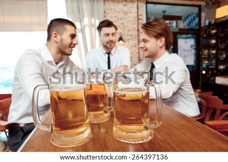 Glass of beer. Close-up of three glasses with beer on the bar with people talking on the background