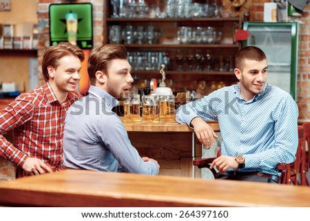 Watching football at the bar. Three handsome young men in casual wear looking away while standing at the bar counter