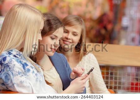 Looking through the pictures. Close-up of three beautiful young women looking at the screen of the smartphone