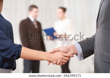 Done deal. Cropped shot of a handshake of a businesswoman and a businessman with other colleagues standing on the background