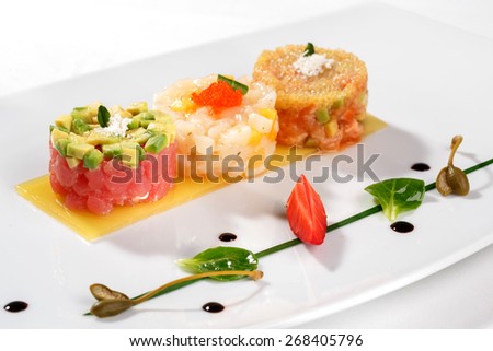 European cuisine. Tartar with tuna fish, avocado, salmon and caviar decorated with strawberry and capers