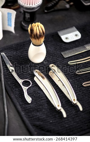 Barber tools. Close-up of elegant old brush with white handle for shaving and range of old-fashioned straight razors on a barbers table