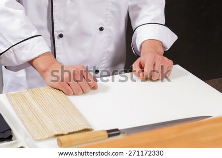 Sushi chef at work. Close-up of hands of a sushi chef getting ready to start cooking sushi rolls