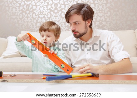 Small architect. Young handsome man and his son playing together with a building constructor and toy level
