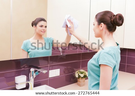 Pedantic. Young woman carefully wiping tap in bathroom with help of yellow cloth