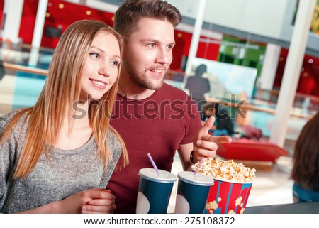 We take it. Young man and woman buying popcorn and coke before watching film in cinema.