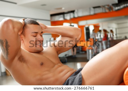 Do your best. Muscular man doing abdominal crunches in sport gym.