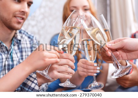 Celebration. Young people clinking glasses of champagne celebrating birthday of their friend selective focus