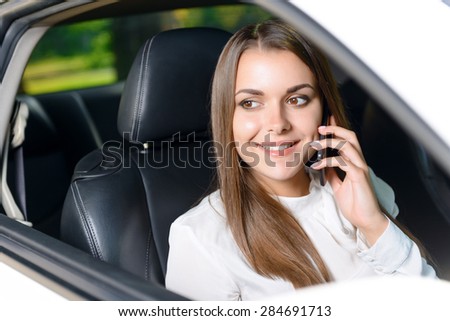 Pleasant conversation. Beautiful youthful woman sitting in car an talking per mobile phone.