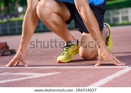 In details. Close up of young runner on start position and going to run forward