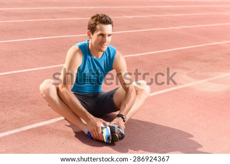 Practice makes perfect. Young attractive man sitting on floor and holding his legs in stretching