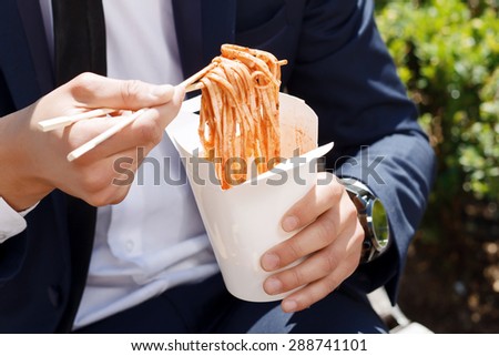Fast food. Close up of businessman holding package with Chinese noodles.
