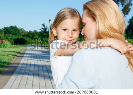 Loving mother. Pretty young mother softly holding her little innocent child in park.
