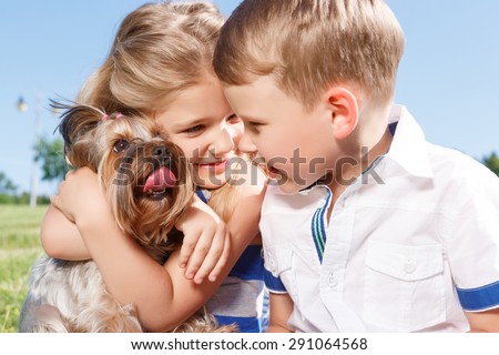Nice time. Upbeat nice little girl embracing the dog and sitting with boy on blanket while expressing positivity.