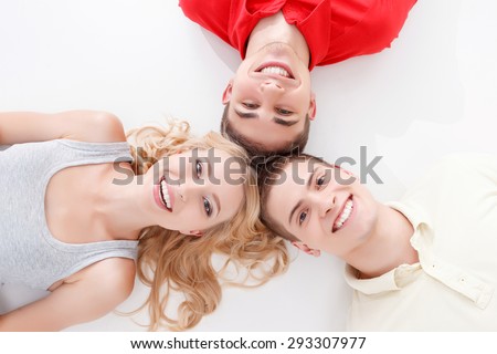 Common mind. Two young handsome men and blond-haired woman lying head to another on white isolated background