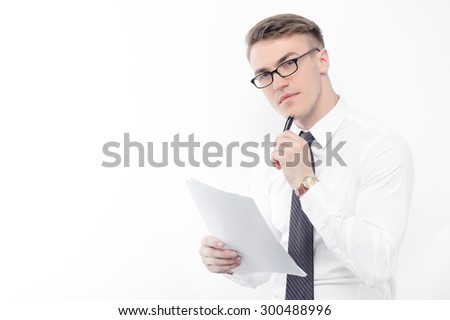 During work. Portrait of young handsome thoughtful businessman standing on white isolated background with papers and pen in his hands