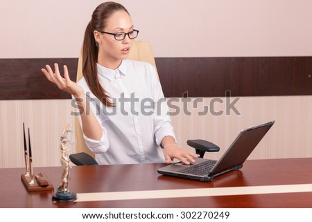 Busy at work. Serious professional worker working on computer and sitting at the table while showing surprise.