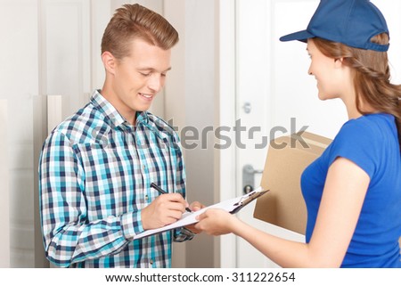 Work to make you happy. Pleasant upbeat charming deliverywoman holding parcel and giving it to client signing papers.