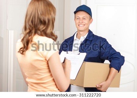 Working for your comfort. Nice hilarious deliveryman holding parcel and expressing positivity while giving it to client