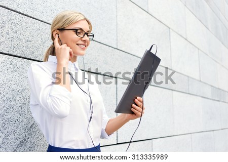 Best way to reduce stress. Blissful upbeat businesswoman holding laptop and wearing headphones while reveling in listening to music