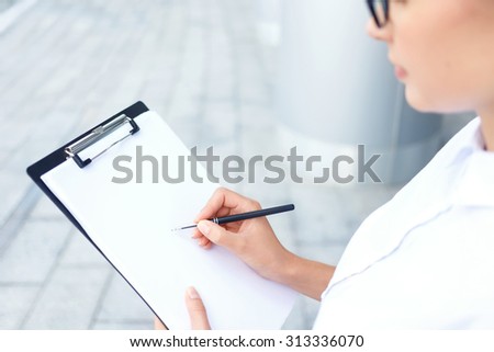 Do your best. Close up of folder in hands of hardworking businesswoman writing and doing her work well